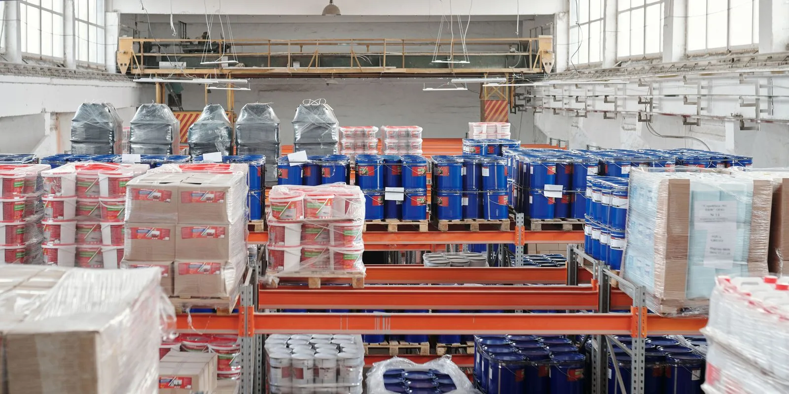 A bright industrial factory floor with packaged goods and pallets