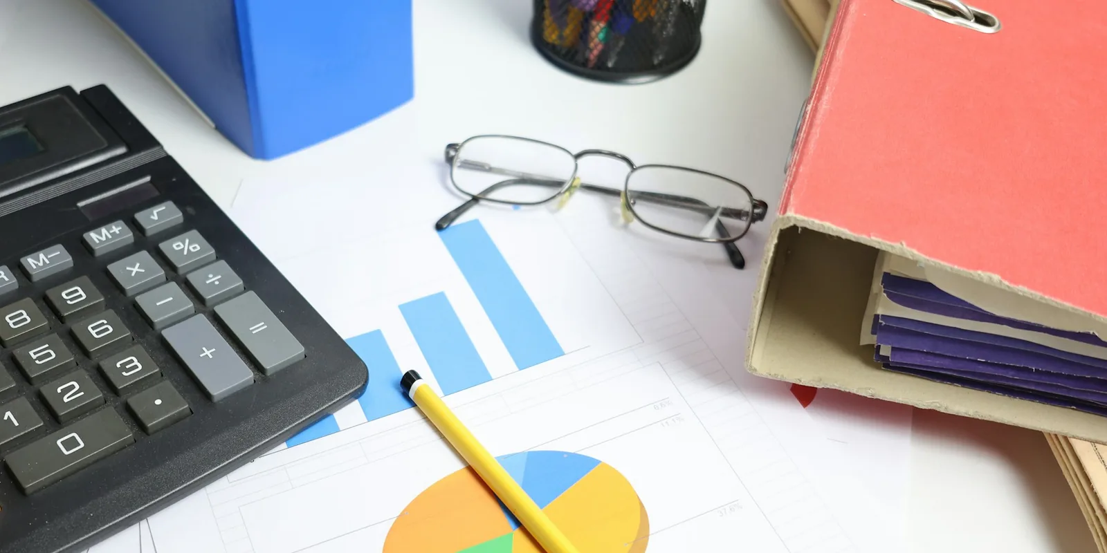 A calculator, charts and reference folders arranged for supplier comparison