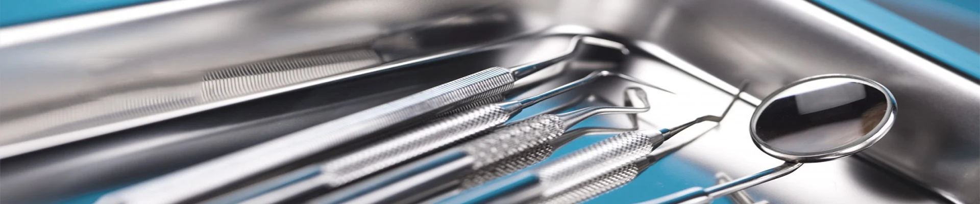 Close-up of polished dental hand instruments arranged in a metal tray